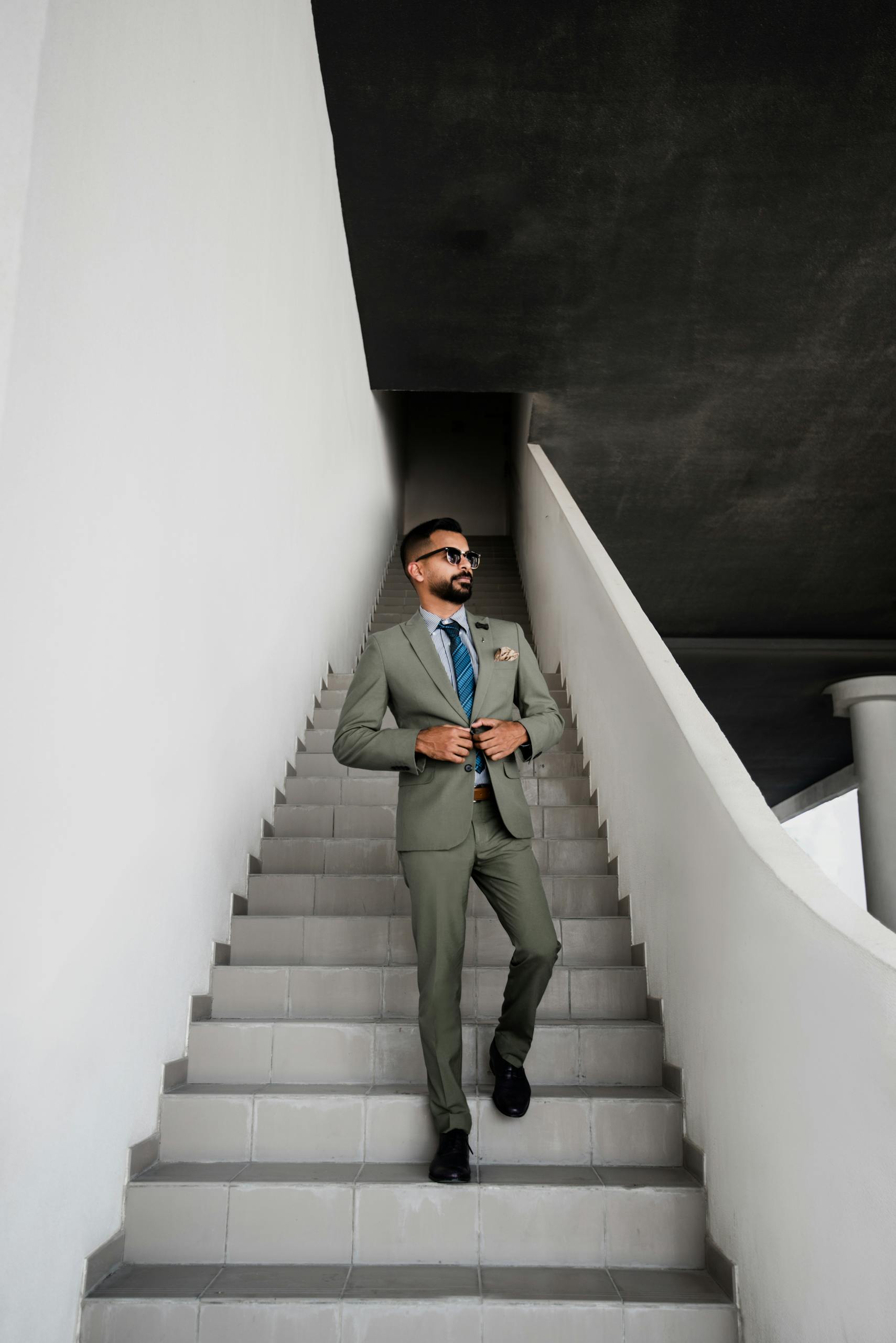 A fashionable man in a suit walking up stairs in Dubai, projecting confidence and style.